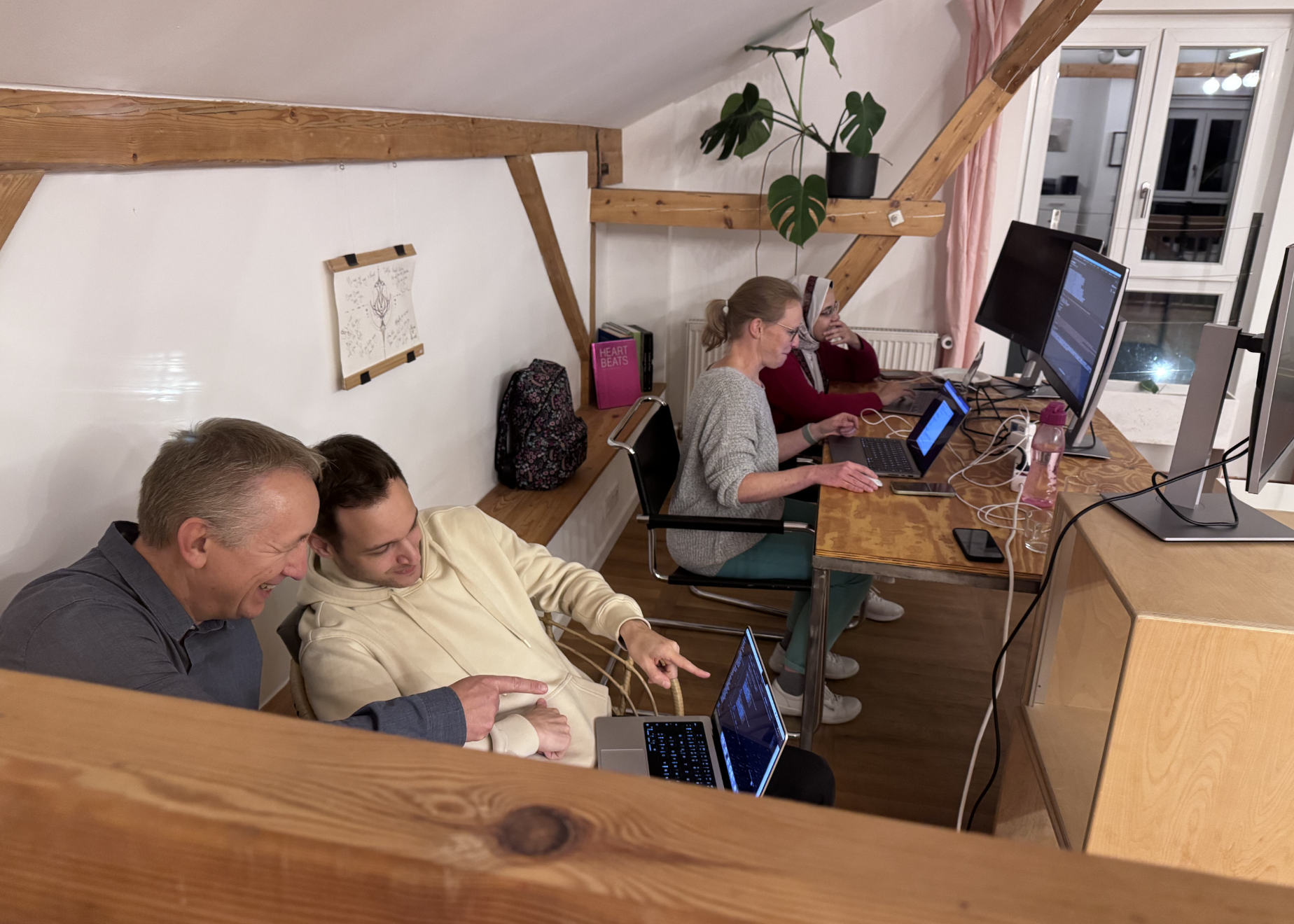 F24 hackathon team members reviewing implementation work together at their desks.