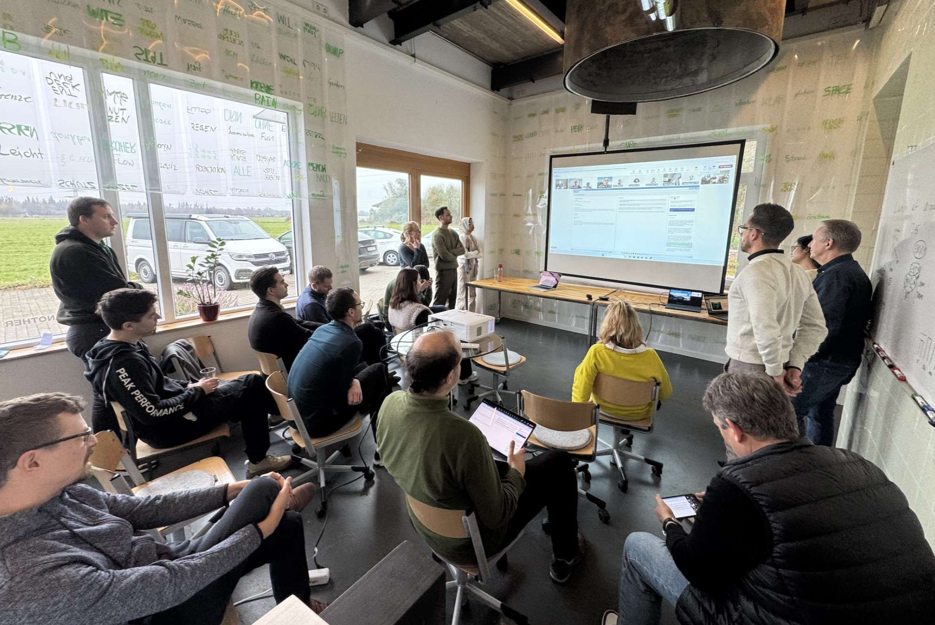 F24 colleagues gathered in a workshop room for an internal AI hackathon presentation.
