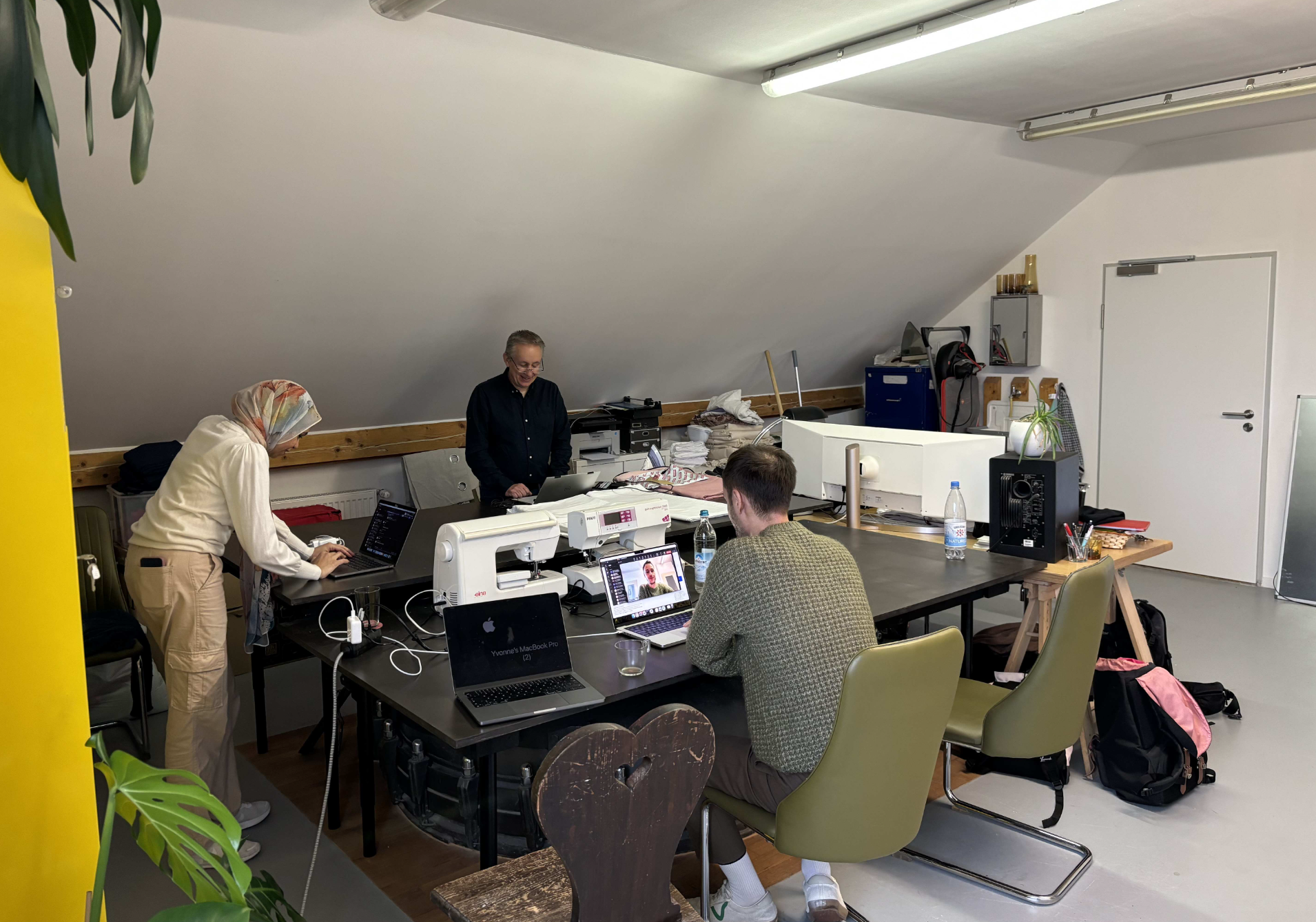 F24 hackathon participants working together around laptops in a shared studio.